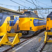 Vooraanzicht van NS-treinen op een spoorlijn, met meerdere treinen zichtbaar in een station