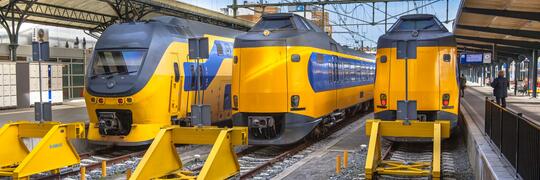 Vooraanzicht van NS-treinen op een spoorlijn, met meerdere treinen zichtbaar in een station