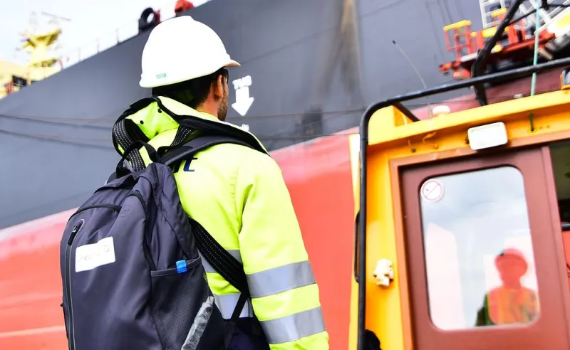 man aan naast schip op de kade