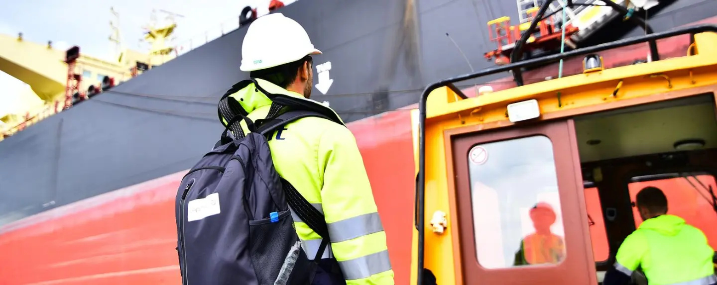 man aan naast schip op de kade